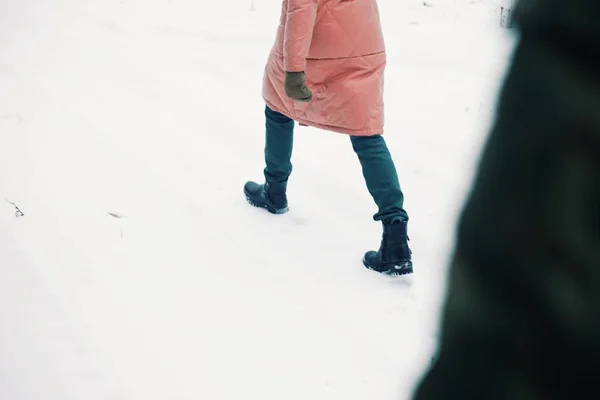 Visa w bland skor i snö. Flickan går i en rosa jacka. Flickor fötter. — Stockfoto