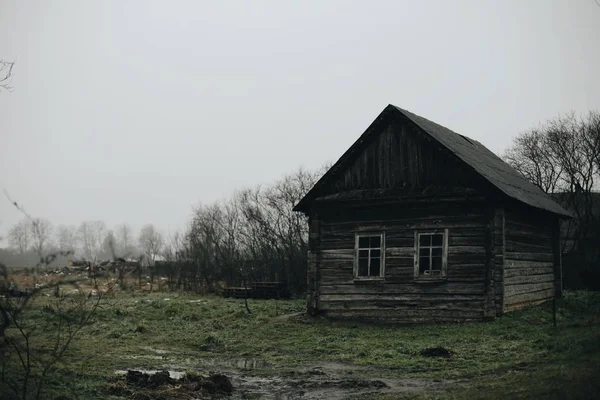 Dřevěný starý dům na jaře. Dirty příroda kolem. — Stock fotografie