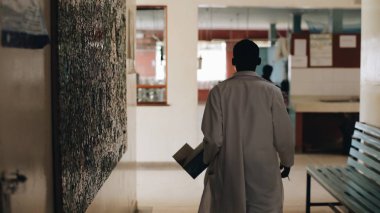 Afrika doktor hastane lobi Afrika köyünde yürürken beyaz tıbbi elbise.