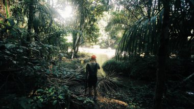Afrika'da orman geçmekte sırt çantaları ile arkadan görünüşü grup beyaz adam. Orman keşfetmek seyahat etmek.