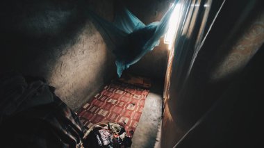 Zavallı küçük bir ev içinde Afrika. Bir sürü kıyafet, keten beton zemin üzerinde yatıyor.