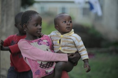 Kenya, Kisumu - 20 Mayıs 2017: arkadan görünüşü Köyü üzerinden çıplak bir bebek taşıyan küçük Afrikalı kız.
