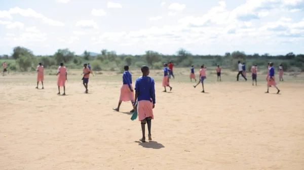 Niños africanos y caucásicos jugando al fútbol afuera juntos . — Foto de Stock