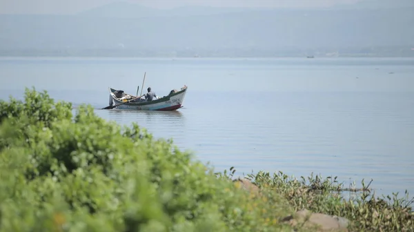 Keňa, Kisumu - 20 května 2017: Africký muž seděl v lodi a veslování sám. Rybář pracuje v moři. — Stock fotografie