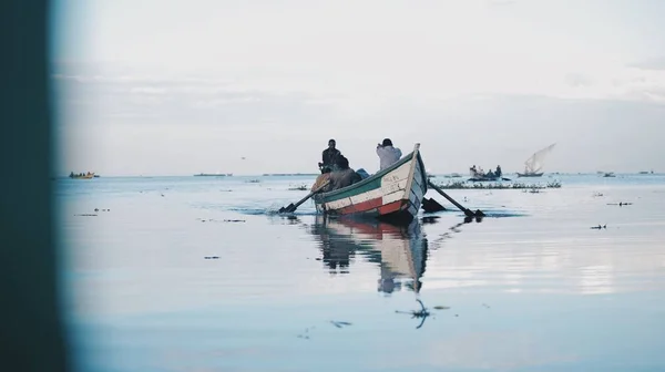 Kenia, Kisumu - 20 mei 2017: Afrikaanse mannen zitten in de boot. Mannen werken, vissen. Bedrijf van de lokale bevolking in Afrika. — Stockfoto