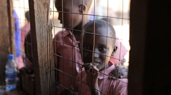 KENIA, KISUMU - 20 DE MAYO DE 2017: Hermosos chicos africanos se asoman a una casa a través de la celosía en la ventana . — Foto de Stock