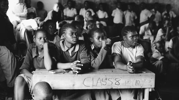 KENYA, KISUMU - MAIO 20, 2017: Grupo de crianças africanas de uniforme sentadas em sala de aula e olhando em linha reta, sorrindo . — Fotografia de Stock
