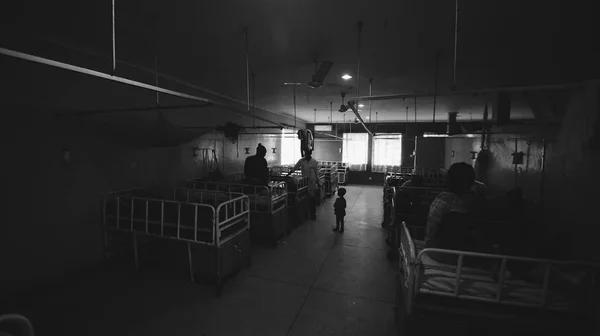 African people with their children sitting on the beds in little hospital in Africa, talking. Black and white Stock Picture