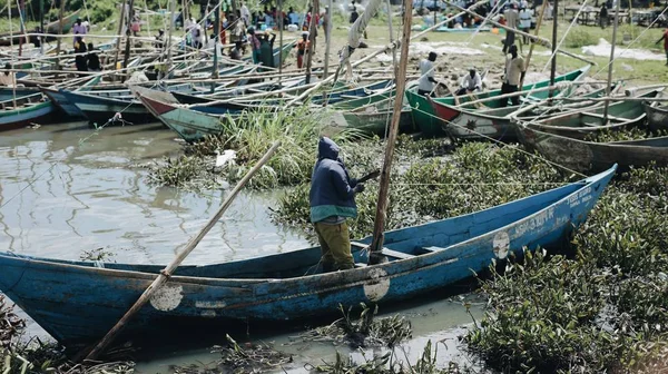 Kenia, Kisumu - 20 maja 2017: Afrykańskiego człowieka żagle na statku płynącego przez rzekę brudne. Rybak działa na łodzi na letni dzień w Afryce. Obrazy Stockowe bez tantiem