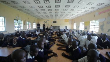 Kenya, Kisumu - 23 Mayıs 2017: Afrikalı çocuklar ve gençler oturan büyük grup, bilezik yapmak beyaz gönüllü yardım