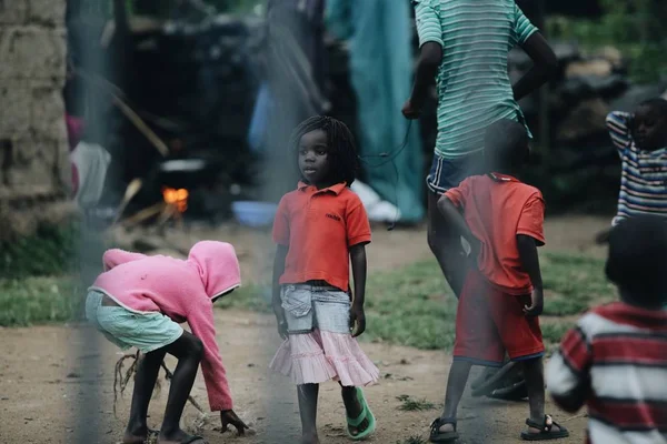 KENIA, KISUMU - 20 DE MAYO DE 2017: Vista a través de la valla. Grupo de africanos que pasan tiempo afuera. Niña divirtiéndose . — Foto de Stock