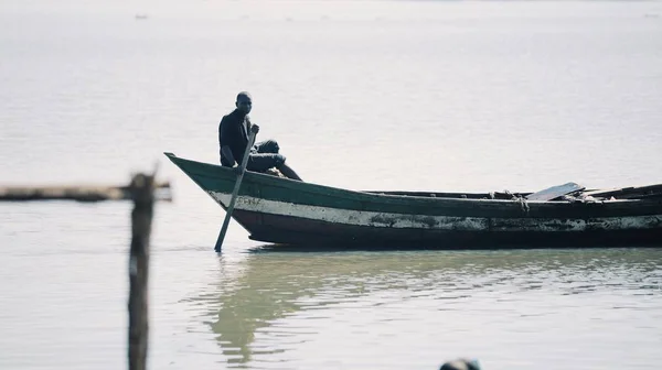 Keňa, Kisumu - 20 května 2017: Mladý africký muž, rybář sedí v lodi sám a veslování v moři. — Stock fotografie