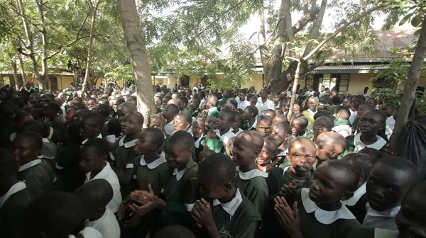 KENYA, KISUMU - 23 de maio de 2017: Grande multidão de crianças africanas de uniforme sentadas em um chão do lado de fora perto da escola . — Fotografia de Stock
