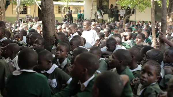 KENYA, KISUMU - 23 de maio de 2017: Grande multidão de crianças africanas de uniforme sentadas em um chão do lado de fora perto da escola . — Fotografia de Stock