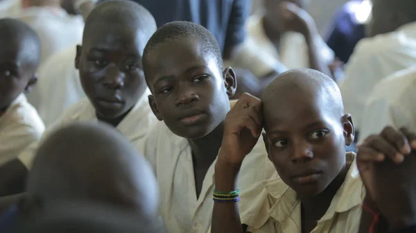KENYA, KISUMU - 23 de maio de 2017: Vista de perto de três meninos africanos de uniforme sentados em sala de aula na escola — Fotografia de Stock