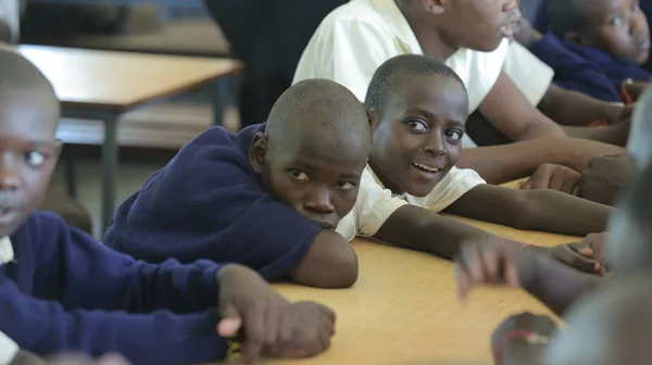 KENYA, KISUMU - 23 de maio de 2017: Vista de perto de três meninos africanos de uniforme sentados em sala de aula na escola — Fotografia de Stock