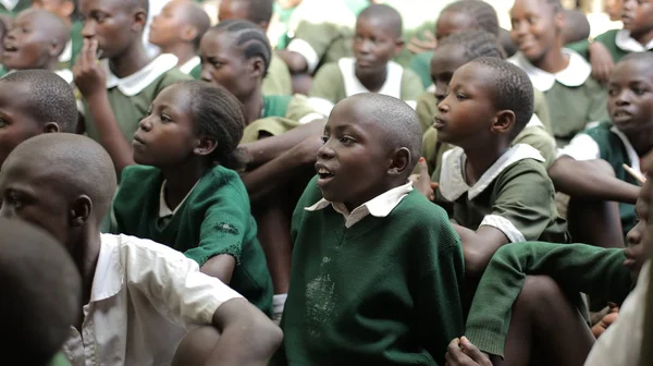 KENYA, KISUMU - 23 de maio de 2017: Grupo de crianças africanas de uniforme verde sentadas no chão, sorrindo, conversando . — Fotografia de Stock