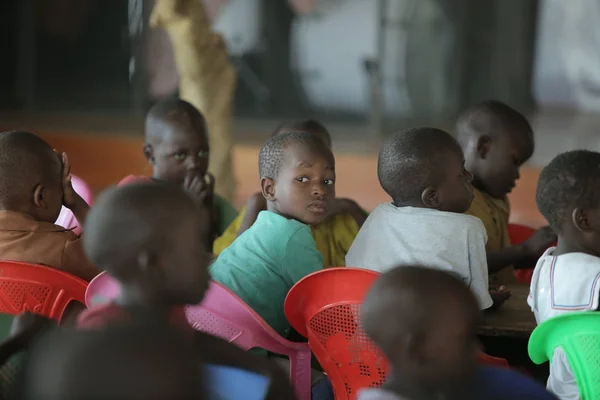 Κένυα, Kisumu - 23 Μαΐου 2017: Πορτρέτο του ευτυχισμένο αγόρι αφρικανικό συνεδρίαση μέσα με ομάδα παιδιών και χορό, χαμογελώντας. — Φωτογραφία Αρχείου