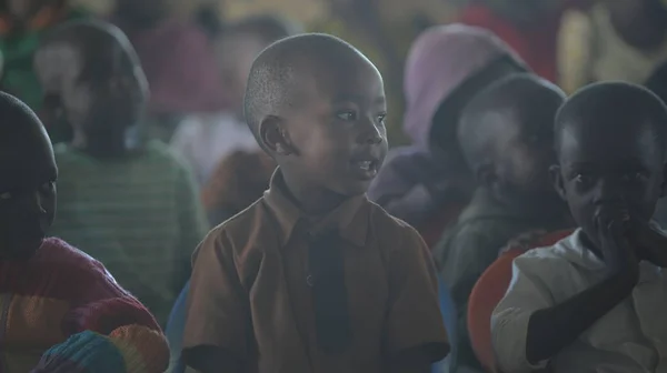 KENIA, KISUMU - 23 DE MAYO DE 2017: Retrato de un niño africano feliz sentado dentro con un grupo de niños y bailando, sonriendo . — Foto de Stock