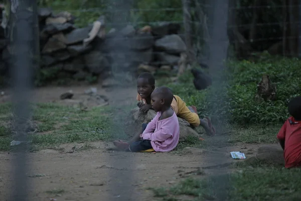 KENIA, KISUMU - 23 DE MAYO DE 2017: Vista a través de la valla. Grupo de africanos que pasan tiempo afuera. Niños divirtiéndose . — Foto de Stock