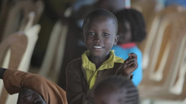 Κένυα, Kisumu - 23 Μαΐου 2017: Πορτρέτο του ευτυχισμένο αγόρι αφρικανικό συνεδρίαση μέσα με ομάδα παιδιών και χορό, χαμογελώντας. — Φωτογραφία Αρχείου