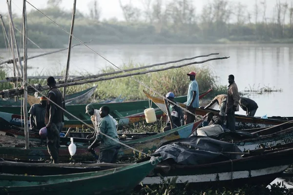 KENYA, KISUMU - MAIO 20, 2017: Vista do porto junto ao rio. Pescadores africanos vão trabalhar de manhã, preparando o barco . Fotos De Bancos De Imagens