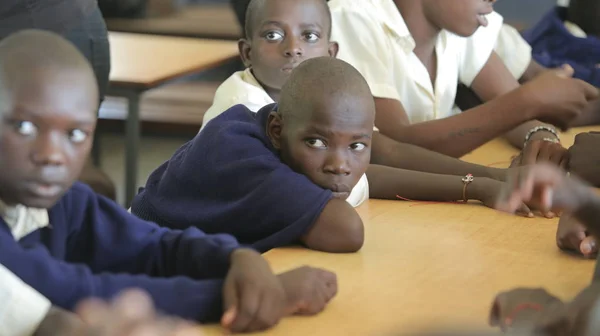 KENYA, KISUMU - MAY 23, 2017: Close-up view of three african boys in uniform sitting in classroom in school Royalty Free Stock Photos