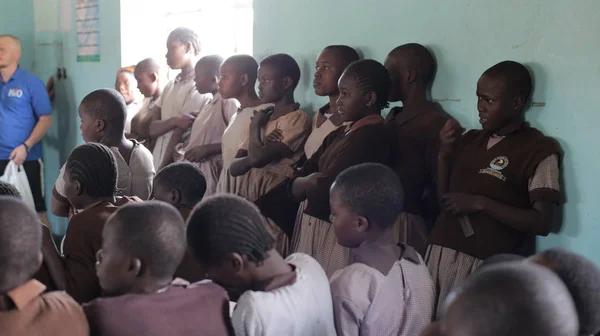 KENYA, KISUMU - MAIO 23, 2017: Grupo de caras africanos fica perto do muro na escola e olha em linha reta. Os rapazes estão a sorrir . Imagens De Bancos De Imagens