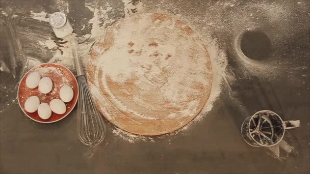 View from above. Closeup of female hands put fresh bread on the table. the flour is scattered around. Eggs lie on a red plate. Beautiful golden round bread — Stock Video