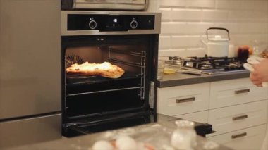 Kadın pizza siyah fırın içine alır. Evde yemek.