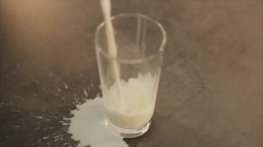 Süt dökülüp cam. Süt cam dökülür. Güzel cam bardak gri bir tablo. Yukarıdan görüntülemek.