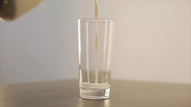 Süt dökülüp cam. Süt cam dökülür. Güzel cam bardak gri bir tablo. Yukarıdan görüntülemek.