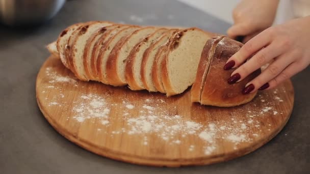 Woman cuts fresh bread on a wooden board. Flour around. Hands with red nails. Close up. — Stock Video