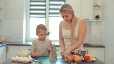 Bir genç güzel beyaz saç ve oğlu ile beyaz anne parlak mutfakta yemek. Anne oğlu yemek yapmayı öğretir.