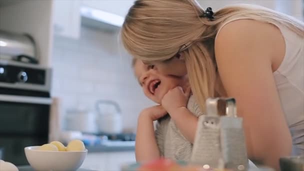 Schattige kleine jongen zoon en zijn mooie moeder spelen en lachen tijdens het kneden van het deeg in de keuken. Concept van de familie vrije tijd in de keuken, het kind bereidt. — Stockvideo