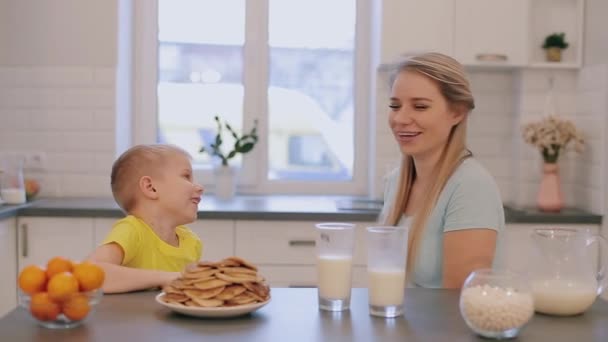 Ευτυχής όμορφη μητέρα Καυκάσιος έχοντας διασκέδαση με το γιο της στην λευκή κουζίνα και δίνοντάς του την παραπέρα. — Αρχείο Βίντεο