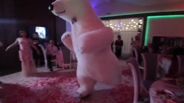 Bielorussia, Minsk - 15 gennaio 2019: Festa di nozze. L'uomo in un grande costume da orso polare sta ballando a un matrimonio con la sposa e gli ospiti. Banchetto di nozze. Petali di fiori volano attraverso la sala . — Video Stock