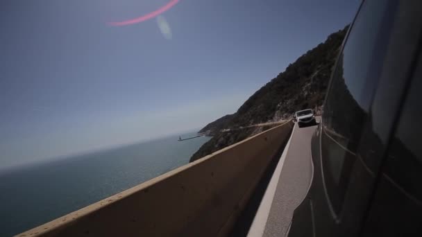 Chiudere lato auto e luce sulla strada. Cielo blu e mare blu. Guida auto sulla strada di montagna. Cavalcate in macchina con la serpentina. Mare Mediterraneo nelle vicinanze . — Video Stock