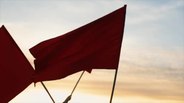 Mains d'un groupe de personnes agitant des drapeaux rouges contre le coucher du soleil . — Video