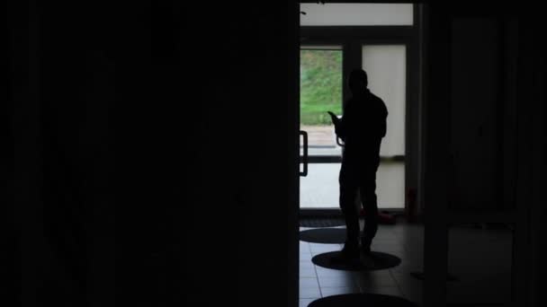 Silhouette of middle aged Caucasian male taling on phone with a door in the background. — Stock Video