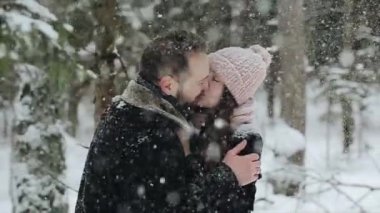 Bir kış ormandaki bir kar altında öpüşme genç güzel çift. Moda millennials eğleniyor toghether. Ormandaki genç çiftin samimi görüntüleri. Ağır çekim.