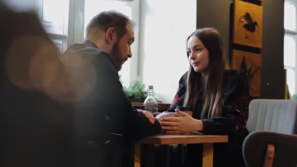 Відверті зображення молода пара в кафе. Кавказький чоловік і жінка сидить з собакою в кафе. Довгий постріл лофт стилі кав'ярень. — стокове відео