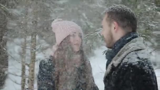 Fiatal gyönyörű kaukázusi pár csók alatt a hó a téli erdőben. Divatos millennials szórakozás toghether. Fiatal pár erdő őszinte felvételek. Lassú mozgás. — Stock videók