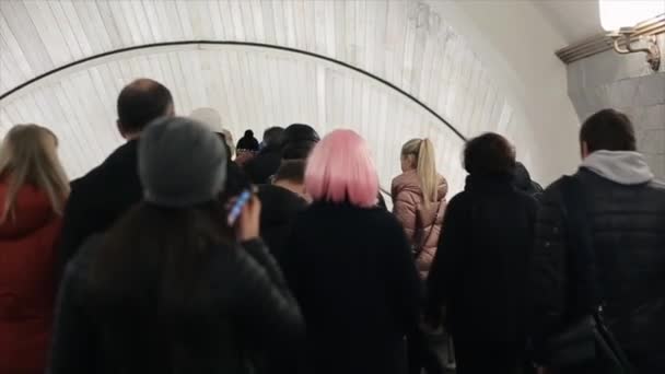 Mooie Kaukasische jong meisje met roze haren gaat door een menigte van mensen in de metro. Vrouw met roze haren draait terug en kijkt naar de camera. — Stockvideo