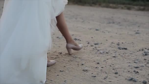 Os pés da noiva nos sapatos caminham na areia . — Vídeo de Stock