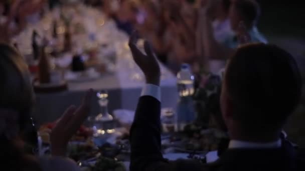 Wit-Rusland, Minsk - mei 30, 2018: Outdoor bruiloft feest met retro garland. Mensen aan de tafel. Bruiloft de feestzaal. Nachttijd. De opstelling van de bruiloft. Bruid en bruidegom funwith gasten. Mensen claping. — Stockvideo