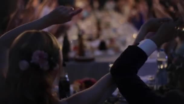 Bielorrusia, Minsk - 30 de mayo de 2018: Fiesta de bodas al aire libre con guirnalda retro. Gente en la mesa. Banquete de bodas. Noche. Configuración de la boda. Novia y novio se divierten con los invitados . — Vídeo de stock