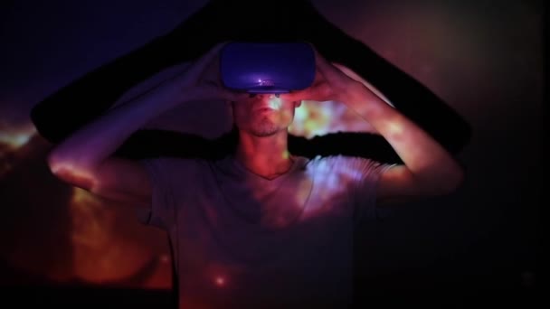 Minsk, Bielorrusia - 11 de junio de 2019: Hombre caucásico guapo con auriculares de realidad virtual con increíbles imágenes virtuales espaciales cósmicas futuristas en el fondo. Guy está disfrutando de la vista — Vídeos de Stock