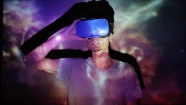Minsk, Belarus - 11 June 2019: Handsome caucasian man wearing virtual reality headset with amazing cosmic futuristic space virtual imaging on background. — Stock Video