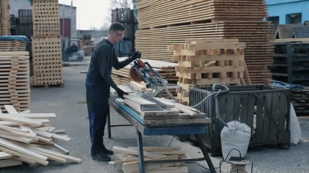 Trabajador industrial joven carpintero utilizando la máquina de corte de madera. hombre corta tablones de madera . — Vídeo de stock